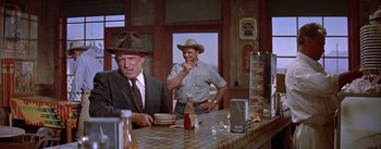 Movie still from “Bad Day at Black Rock” (1955), directed by John Sturges – Two men sitting at a counter in front of a bottle of soda; Medium shot, Over the shoulder angle