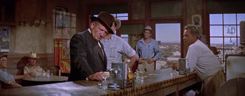 Movie still from “Bad Day at Black Rock” (1955), directed by John Sturges – A man in a suit and a hat at a bar; Medium shot, Over the shoulder angle