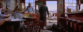 Movie still from “Bad Day at Black Rock” (1955), directed by John Sturges – A man in a suit and a hat standing in front of an open door; Wide shot, Over the shoulder angle