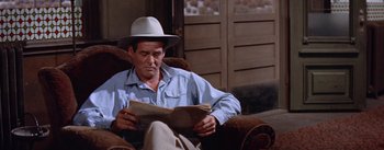 Movie still from “Bad Day at Black Rock” (1955), directed by John Sturges – A man sitting on a chair reading a newspaper; Medium shot, Low angle