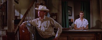 Movie still from “Bad Day at Black Rock” (1955), directed by John Sturges – A man wearing a cowboy hat standing next to a table; Medium shot, Low angle