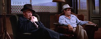 Movie still from “Bad Day at Black Rock” (1955), directed by John Sturges – Two men sitting on a couch in a room; Medium shot, Low angle