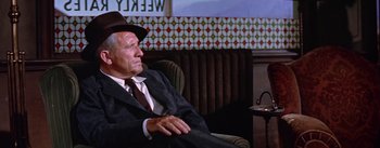 Movie still from “Bad Day at Black Rock” (1955), directed by John Sturges – An older man sitting in a chair wearing a suit and hat; Medium shot, Over the shoulder angle