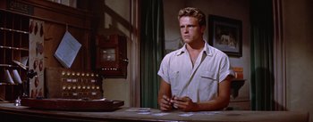 Movie still from “Bad Day at Black Rock” (1955), directed by John Sturges – A man sitting at a table holding a cell phone; Medium shot, Low angle