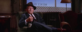 Movie still from “Bad Day at Black Rock” (1955), directed by John Sturges – An older man sitting in a chair holding a bottle of beer; Medium shot, Low angle