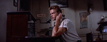 Movie still from “Bad Day at Black Rock” (1955), directed by John Sturges – A man sitting in front of a microphone on the phone; Medium shot, Low angle