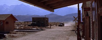 Movie still from “Bad Day at Black Rock” (1955), directed by John Sturges – A truck driving down a dirt road next to mountains; Extreme Wide shot, Low angle