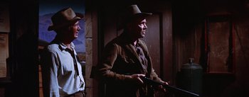 Movie still from “Bad Day at Black Rock” (1955), directed by John Sturges – A man holding a gun while standing next to another man; Medium shot, Low angle