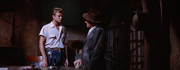 Movie still from “Bad Day at Black Rock” (1955), directed by John Sturges – A man in a suit and hat talking to another man in jeans; Medium shot, Over the shoulder angle