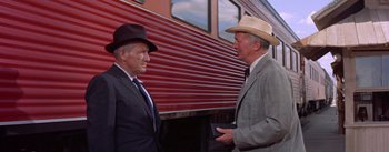 Movie still from “Bad Day at Black Rock” (1955), directed by John Sturges – Two men in suits and cowboy hats standing in front of a train; Medium shot, Over the shoulder angle