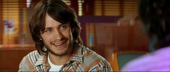 Movie still from “Bad Education” (2004), directed by Pedro Almodóvar – A person wearing a plaid shirt smiling; Close Up shot, Over the shoulder angle