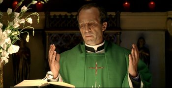 Movie still from “Bad Education” (2004), directed by Pedro Almodóvar – A man in a green robe is praying; Close Up shot, Low angle