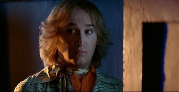 Movie still from “Bad Education” (2004), directed by Pedro Almodóvar – A man with long blonde hair wearing a neck tie; Close Up shot, Over the shoulder angle