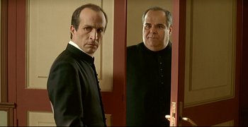 Movie still from “Bad Education” (2004), directed by Pedro Almodóvar – A man standing in front of a mirror in a room; Medium shot, Over the shoulder angle