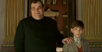 Movie still from “Bad Education” (2004), directed by Pedro Almodóvar – A man and a young boy standing next to each other; Medium shot, Low angle