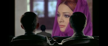 Movie still from “Bad Education” (2004), directed by Pedro Almodóvar – Two men sitting in front of a woman's face on a screen; Close Up shot, Over the shoulder angle