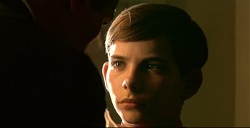 Movie still from “Bad Education” (2004), directed by Pedro Almodóvar – A person with short brown hair is looking at the camera; Close Up shot, Over the shoulder angle