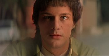 Movie still from “Bad Education” (2004), directed by Pedro Almodóvar – A young man is looking into the camera; Close Up shot, Over the shoulder angle