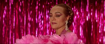 Movie still from “Bad Education” (2004), directed by Pedro Almodóvar – A woman in a pink feather dress with a pink background; Close Up shot, Low angle