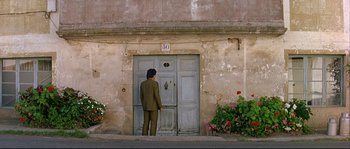 Movie still from “Bad Education” (2004), directed by Pedro Almodóvar – A man standing in front of an old door; Wide shot, Low angle