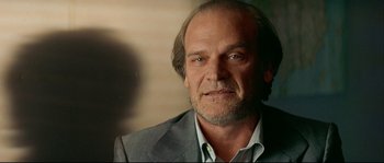 Movie still from “Bad Education” (2004), directed by Pedro Almodóvar – An older man in a gray suit is looking at the camera; Close Up shot, Low angle