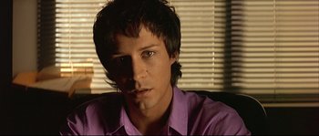 Movie still from “Bad Education” (2004), directed by Pedro Almodóvar – A young man in a purple shirt is looking at the camera; Close Up shot, Low angle