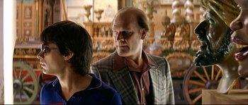 Movie still from “Bad Education” (2004), directed by Pedro Almodóvar – A man in a plaid jacket talking to another man; Medium shot, Over the shoulder angle