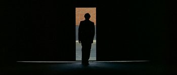 Movie still from “Bad Education” (2004), directed by Pedro Almodóvar – A man standing in front of an open door; Wide shot, Low angle