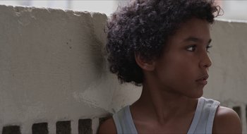 A young woman with curly hair leaning against a wall