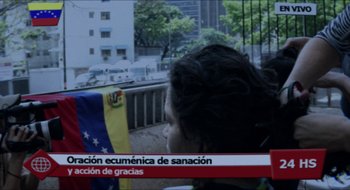 Movie still from “Bad Hair” (2013), directed by Mariana Rondón – A woman sitting in a chair in front of a building; Extreme Wide shot, High angle