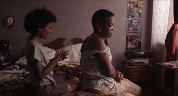 Two women sitting on a bed in front of each other