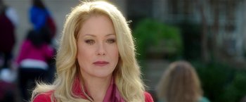 Movie still from “Bad Moms” (2016), directed by Scott Moore – A woman with blonde hair wearing a pink shirt and a pink scarf; Close Up shot, Over the shoulder angle