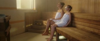 Movie still from “Bad Moms” (2016), directed by Scott Moore – Two women sitting on a wooden bench in a sauna; Medium shot, High angle