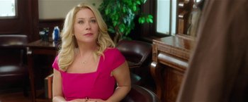 Movie still from “Bad Moms” (2016), directed by Scott Moore – A woman in a pink dress sitting in front of a desk; Medium shot, Over the shoulder angle