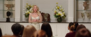 Movie still from “Bad Moms” (2016), directed by Scott Moore – A woman standing in front of a group of people in a room; Medium shot, Over the shoulder angle