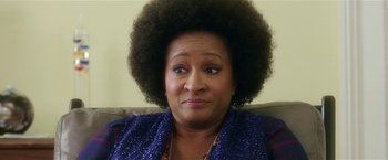 An older woman with an afro is sitting on a couch