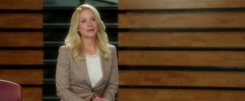 Movie still from “Bad Moms” (2016), directed by Scott Moore – A blonde woman in a brown suit sitting in front of a wooden wall; Close Up shot, Over the shoulder angle