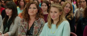 Movie still from “Bad Moms” (2016), directed by Scott Moore – Two women sitting next to each other in front of a group of people; Close Up shot, Over the shoulder angle