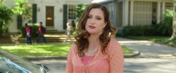 Movie still from “Bad Moms” (2016), directed by Scott Moore – A woman in a pink dress standing in front of a house; Medium shot, Over the shoulder angle