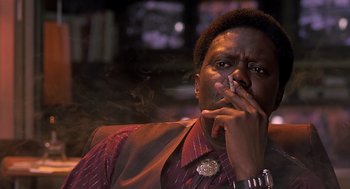 Movie still from “Bad Santa” (2003), directed by Terry Zwigoff – A man smoking a cigarette while sitting in a chair; Close Up shot, Low angle