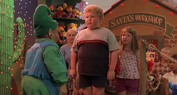 Movie still from “Bad Santa” (2003), directed by Terry Zwigoff – A group of people standing next to each other in a room; Medium shot, Over the shoulder angle