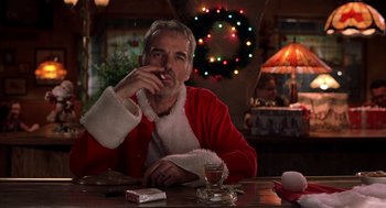 Movie still from “Bad Santa” (2003), directed by Terry Zwigoff – A man sitting at a table with a cigarette in his mouth; Medium shot, Low angle