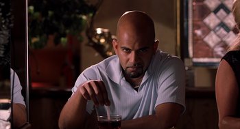Movie still from “Bad Santa” (2003), directed by Terry Zwigoff – A bald man sitting in front of a glass of beer; Close Up shot, Low angle
