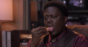 Movie still from “Bad Santa” (2003), directed by Terry Zwigoff – A man eating a donut with a bite taken out of it; Close Up shot, High angle