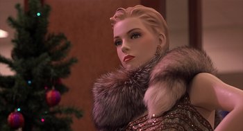 Movie still from “Bad Santa” (2003), directed by Terry Zwigoff – A mannequin wearing a fur coat and earrings with a christmas tree in the background; Close Up shot, Low angle