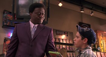 Movie still from “Bad Santa” (2003), directed by Terry Zwigoff – A man in a purple suit talking to a young boy; Medium shot, Over the shoulder angle