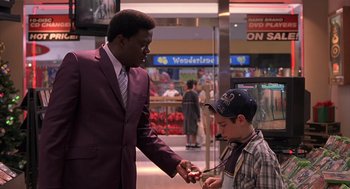 Movie still from “Bad Santa” (2003), directed by Terry Zwigoff – A man in a purple suit and a boy in a blue hat; Medium shot, Over the shoulder angle