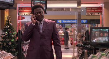 Movie still from “Bad Santa” (2003), directed by Terry Zwigoff – A man in a suit talking on a cell phone; Medium shot, Low angle