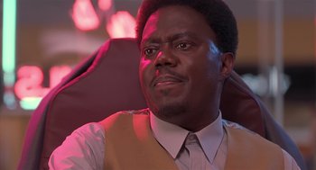 Movie still from “Bad Santa” (2003), directed by Terry Zwigoff – A person sitting in a chair wearing a vest; Close Up shot, Low angle