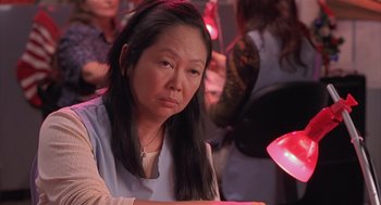 Movie still from “Bad Santa” (2003), directed by Terry Zwigoff – A woman sitting in front of a table with other people around her; Close Up shot, High angle